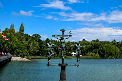 Statue by river against sky