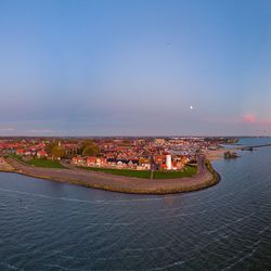 Illuminated city by sea against blue sky urk netherlands 