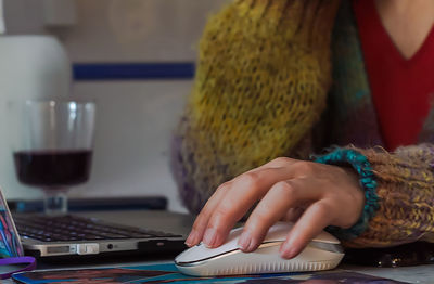 Midsection of woman using computer mouse on table