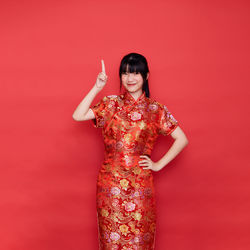 Portrait of a smiling young woman against red background