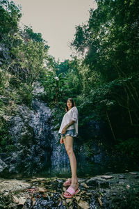 Woman standing on rock against trees