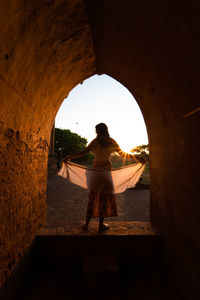 Rear view of woman sitting at archway