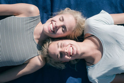 High angle view of smiling friends lying on bed