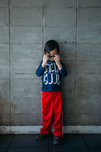 Full length portrait of boy in sunglass standing against wall