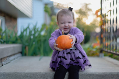 Girl laughing while holding pumpkin on land
