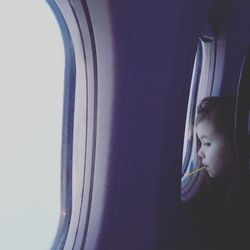 Portrait of cute boy looking through airplane window