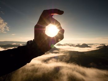 Low angle view of silhouette man standing on mountain against sky during sunset