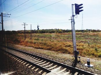 Electricity pylons on field against blue sky