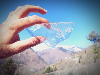 Close-up of hand holding ice cream against mountain