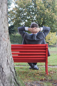 Businessman relaxing on a red park bench