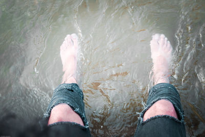 Low section of man wearing torn jeans in river