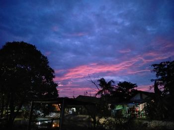 Silhouette trees and buildings against sky at sunset