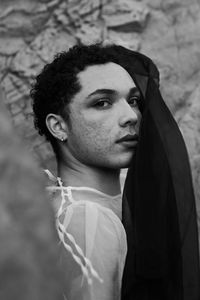 Young male with  androgynous look shot outdoor in black and white with rocks in background.