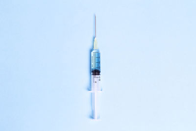 Close-up of syringe against blue background