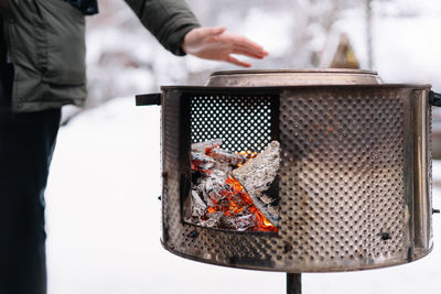 Man warming hands over coal stove during winter