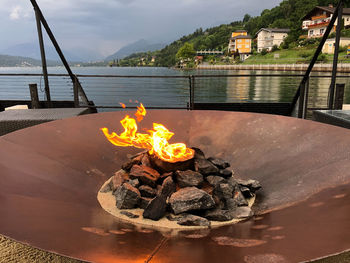 Bonfire on wooden structure in lake against sky