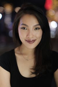 Portrait of beautiful woman smiling against illuminated lights at night