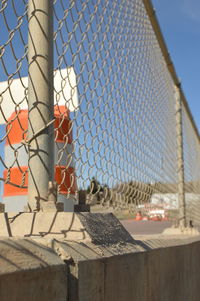 Traffic cones on road seen through chainlink fence