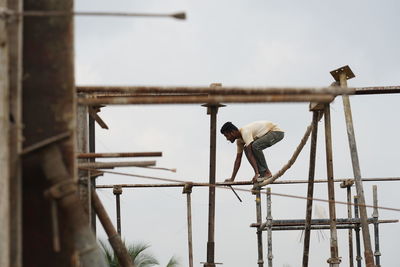 Low angle view of man at construction site against sky