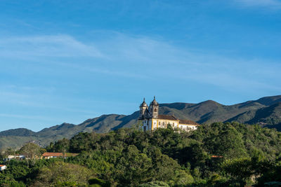 Scenic view of building and mountains against blue sky