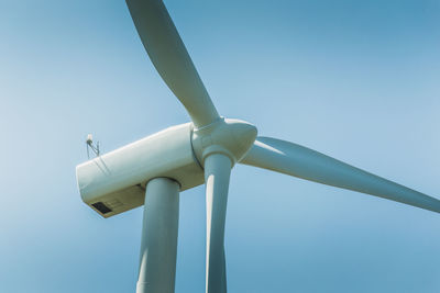 Low angle view of wind turbine against clear blue sky