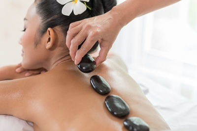 Therapist placing hot stones on woman back in spa
