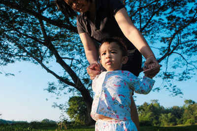 Portrait of mother and daughter against trees