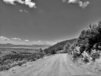 Empty road along landscape and trees against sky