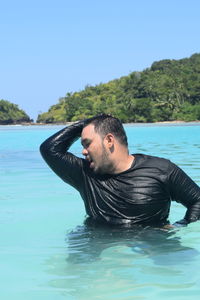 Portrait of young man in swimming pool against sea