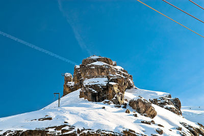 Low angle view of snow covered mountain against blue sky