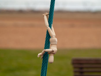 Close-up of wooden figurine hanging on rope