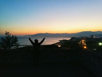 Silhouette man on shore against sky during sunset