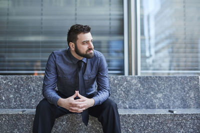 Full length of young man sitting at camera