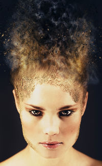 Close-up portrait of young woman over black background