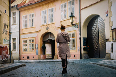 Rear view of woman walking on street amidst buildings