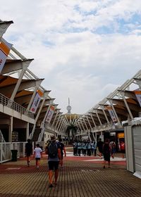 People walking in town square against cloudy sky