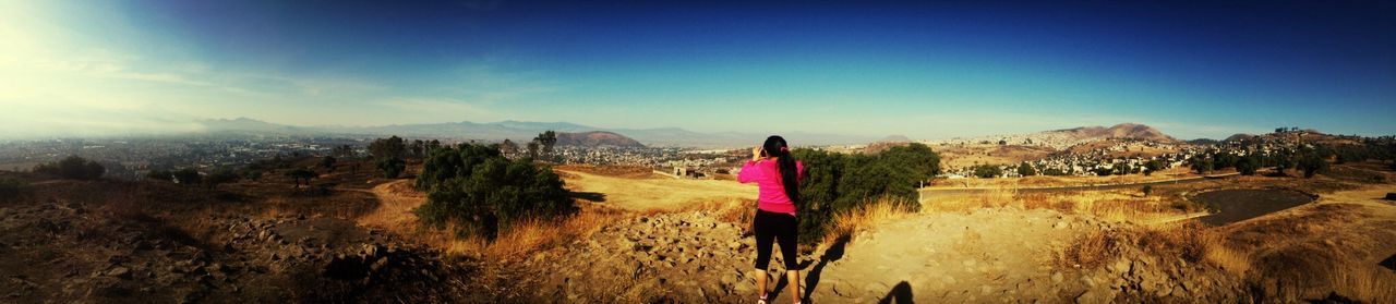 landscape, mountain, sky, tranquil scene, scenics, leisure activity, tranquility, blue, beauty in nature, lifestyles, rear view, nature, red, full length, non-urban scene, person, remote, mountain range