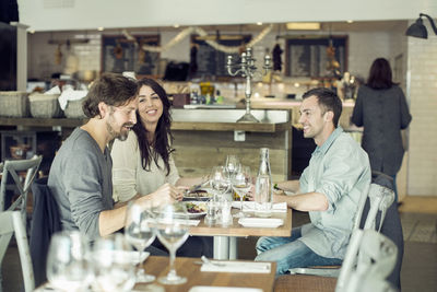 Happy friends discussing at restaurant table