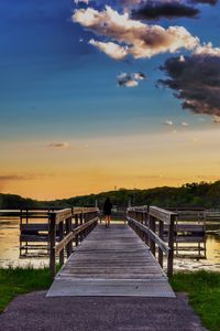 Man on pier against sky during sunset