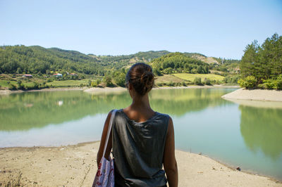 Rear view of woman standing against lake