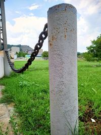 Close-up of chain on wooden post in field