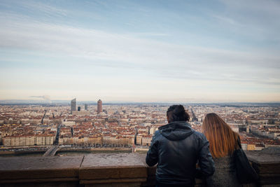 Rear view of woman looking at cityscape against sky