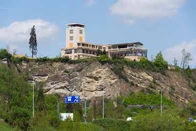 Information sign by building against sky