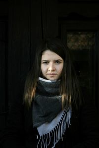 Portrait of beautiful young woman standing in dark room