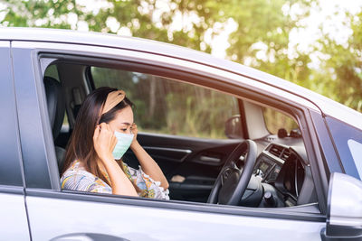 Side view of woman wearing mask sitting in car