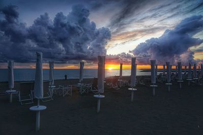 Chairs on beach against sky during sunset