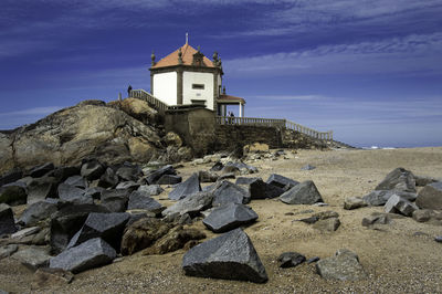 High angle view of cross on rock by building against sky