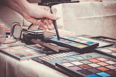 Close-up of woman hand holding make-up brush over palette