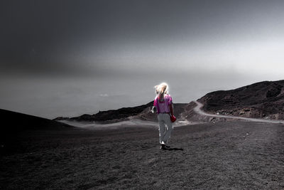 Woman walking on land against sky