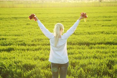 Rear view of woman standing in field with flowers